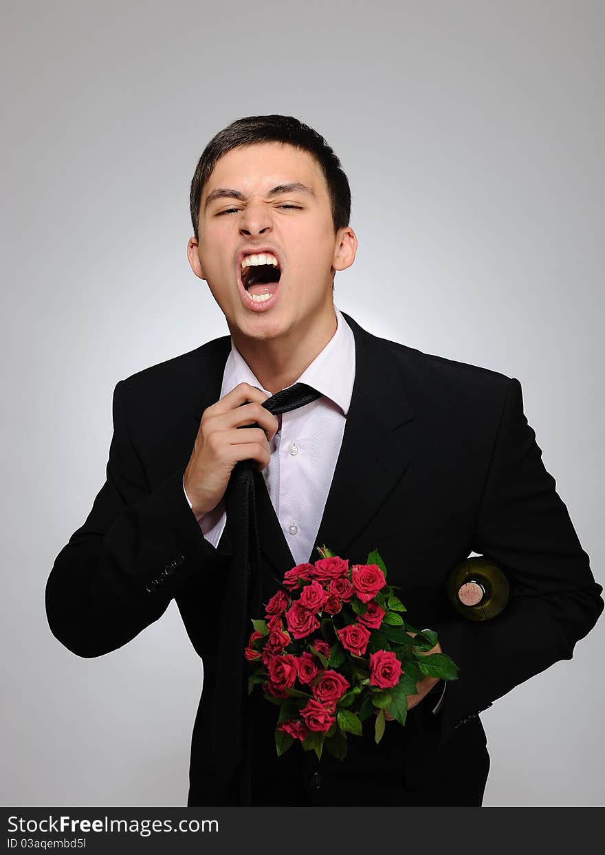 Handsome romantic young man holding rose flower and vine bottle prepared for a valentines day. gray background. Handsome romantic young man holding rose flower and vine bottle prepared for a valentines day. gray background