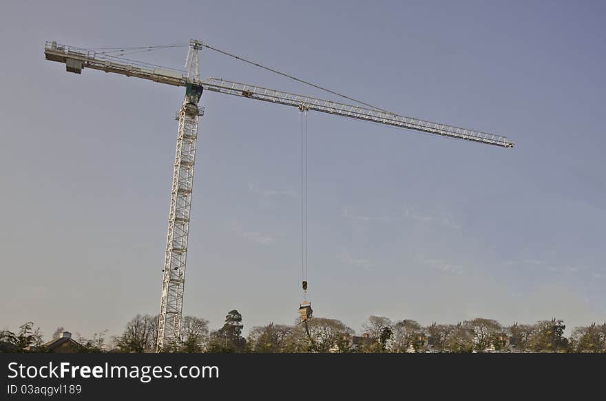 Tall white tower crane against bright blue sky. Tall white tower crane against bright blue sky.