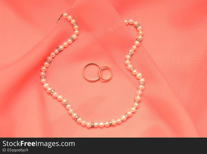 Photo of a silk fabric, pearls and rings. Photo of a silk fabric, pearls and rings