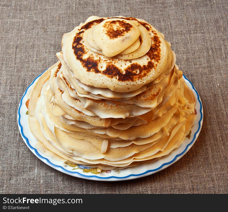 Pile of pancakes with an oil slice on a round plate