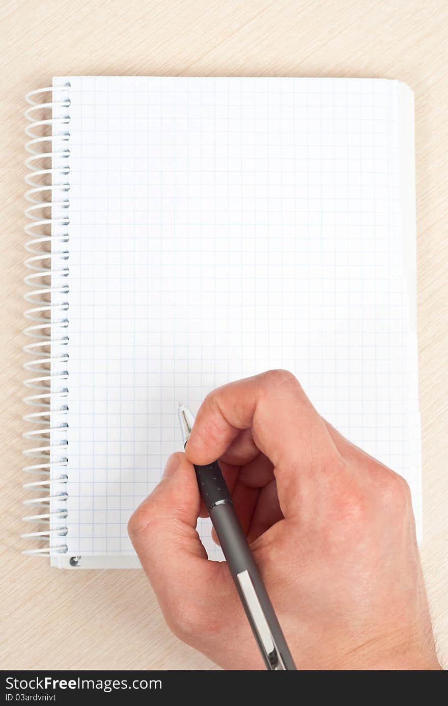 Male hand holding a pen writing notes in a notebook. Male hand holding a pen writing notes in a notebook.