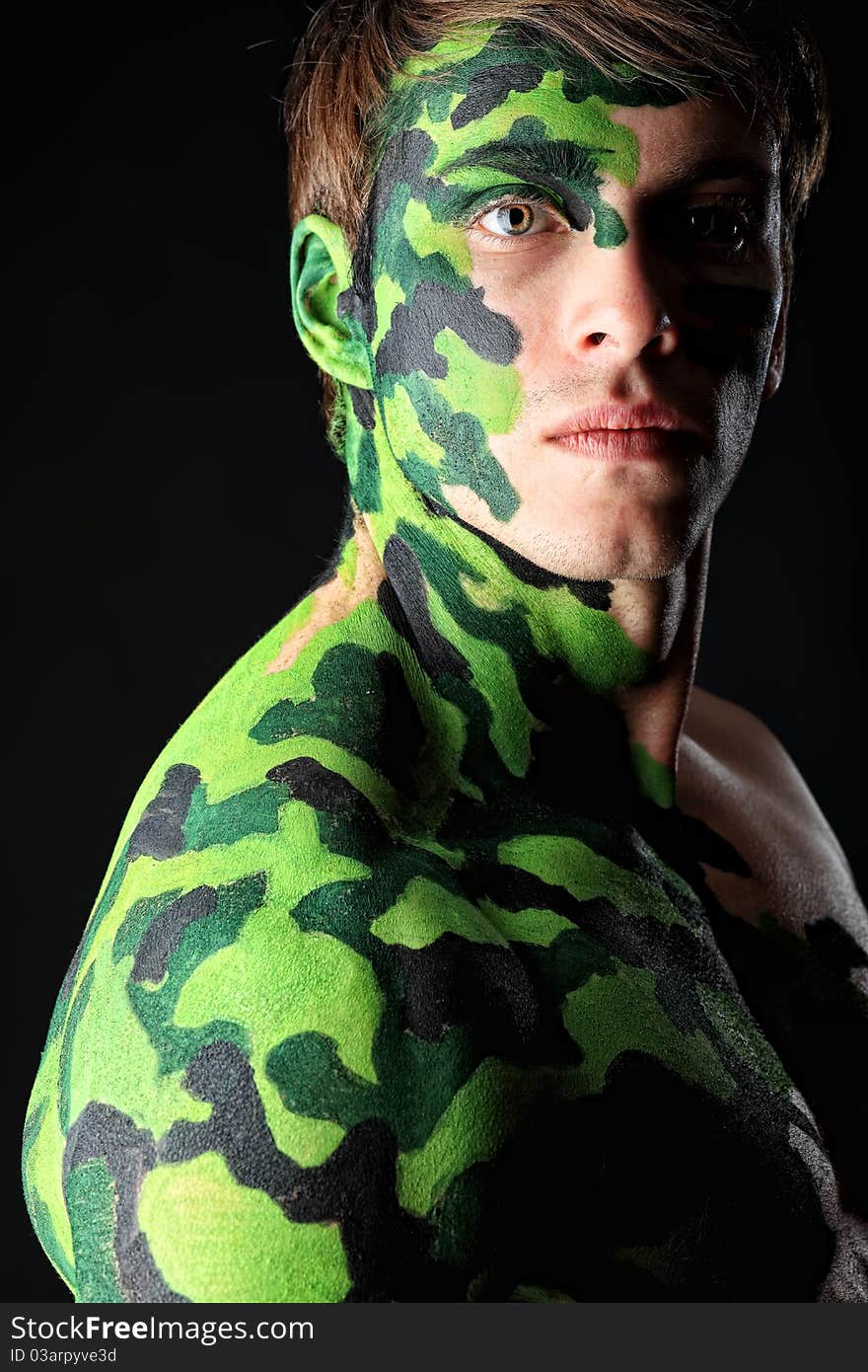 Shot of a conceptual soldier painted in khaki colors. Studio shot over black background.