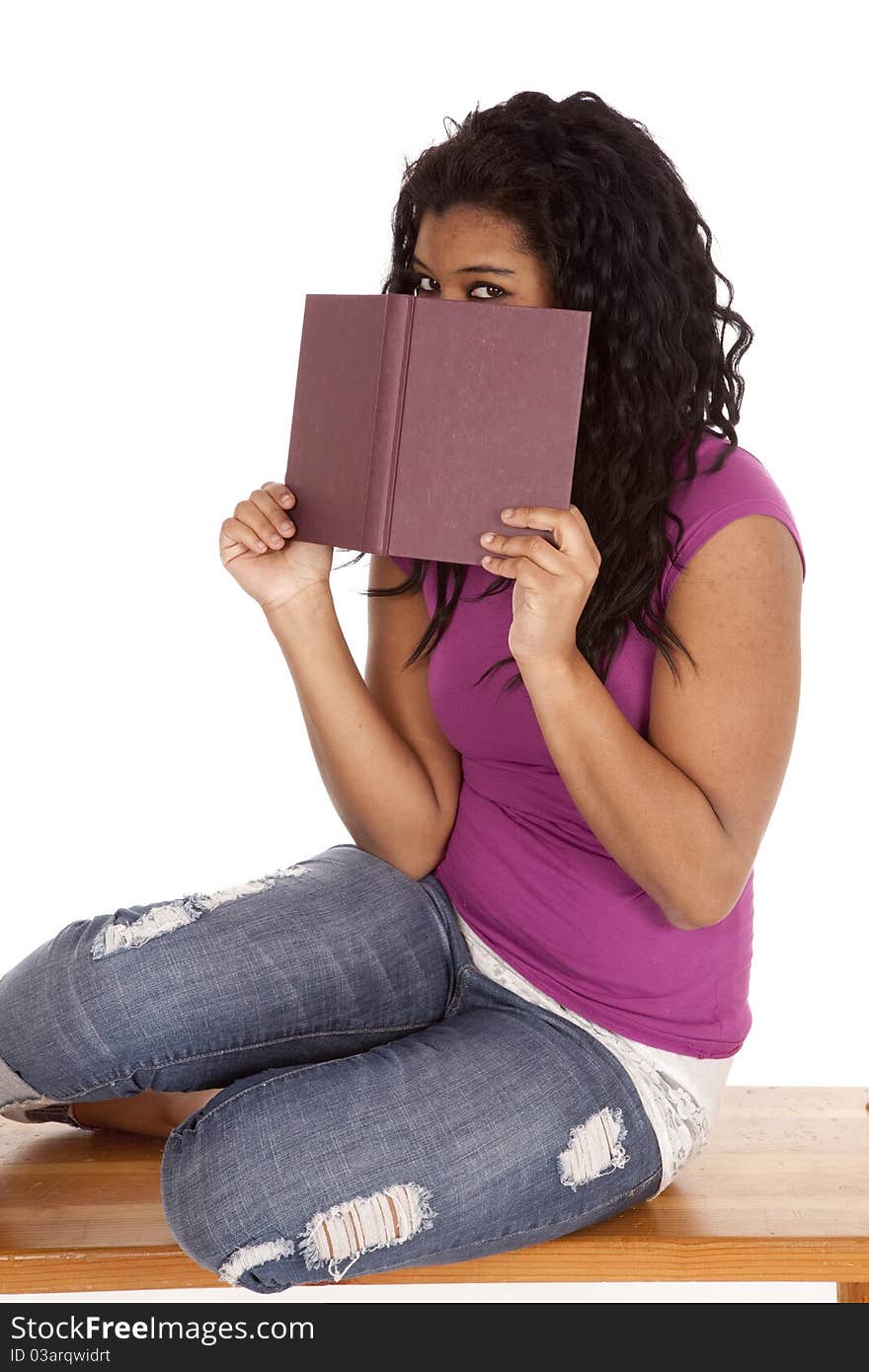 An African American woman is peaking over a book. An African American woman is peaking over a book.