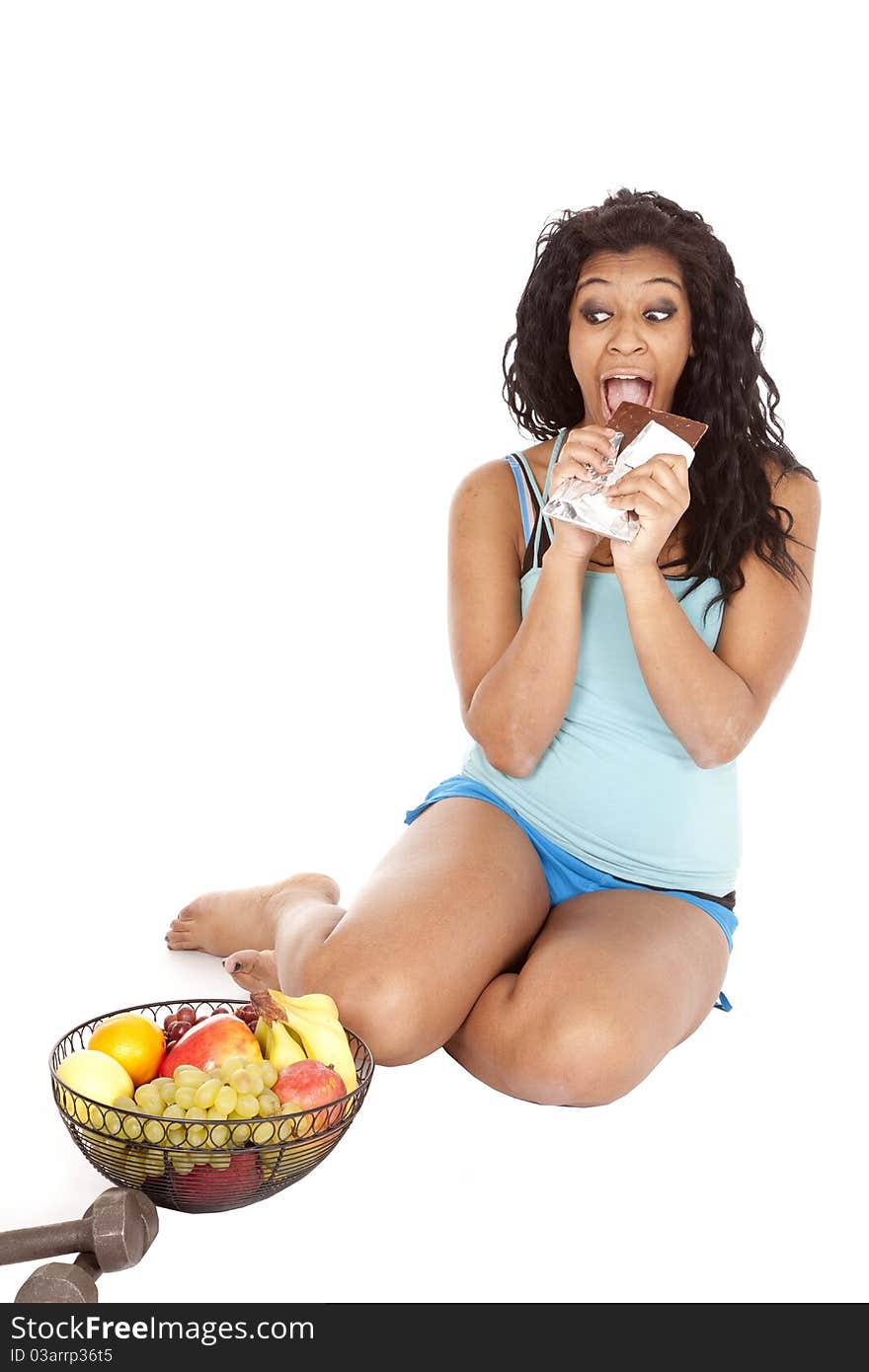 Woman eating chocolate looking at fruit