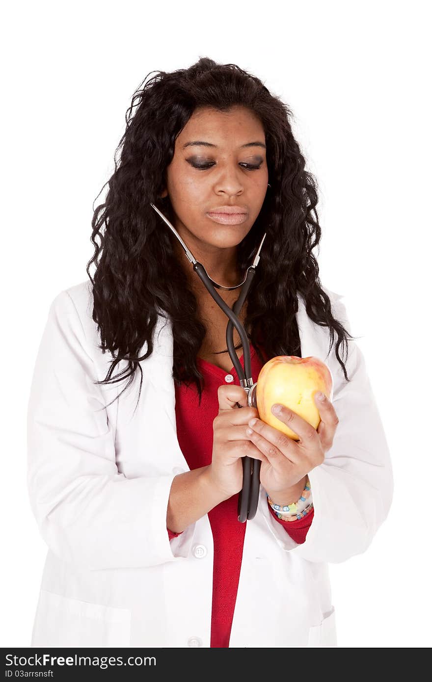 A Woman with a stethoscope is looking down at an apple. A Woman with a stethoscope is looking down at an apple.