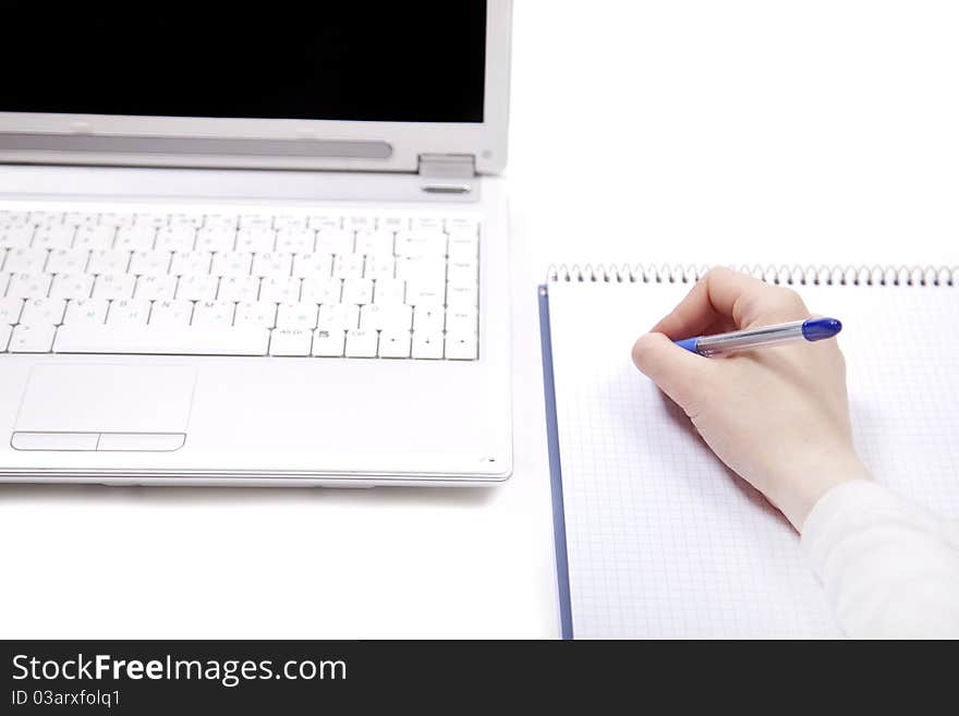 Business notebook with laptop and pen in hand.