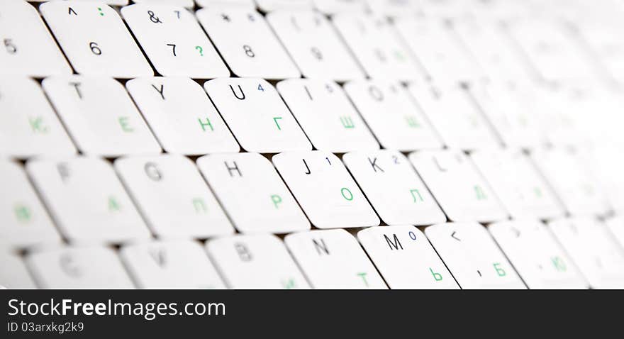 Close-up view at laptop keyboard with english and russian letters.