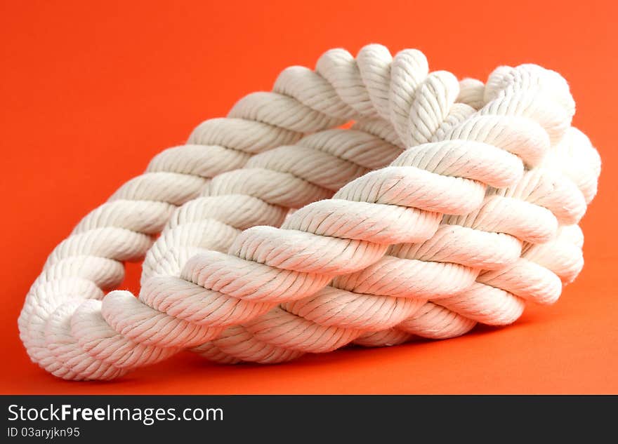 Close-up of a twisted white cable on red background