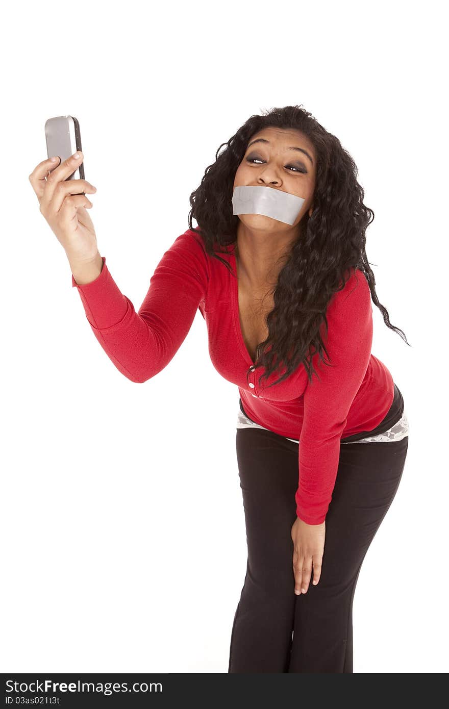 An African American woman has a phone and is taking a picture with her mouth taped shut. An African American woman has a phone and is taking a picture with her mouth taped shut.