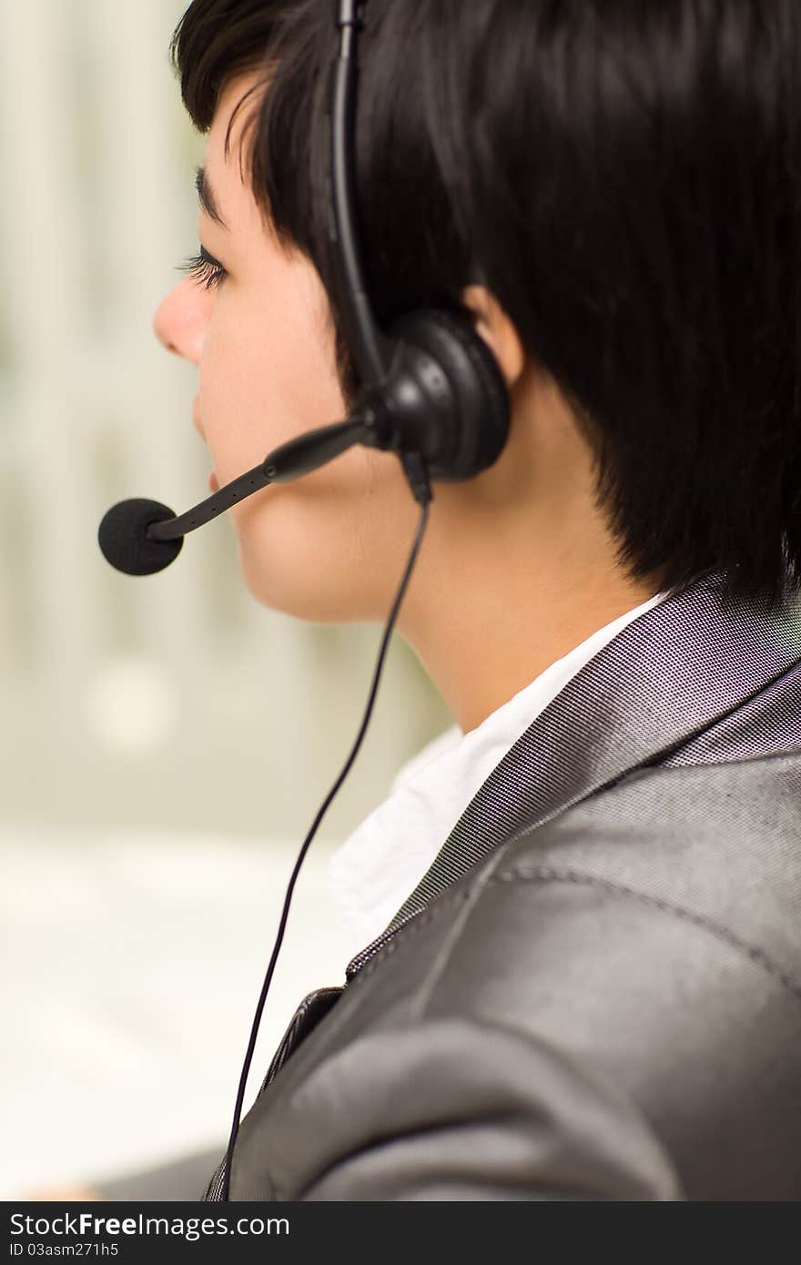 Profile of an Attractive Young Mixed Race Woman Smiles Wearing Headset In An Office Setting. Profile of an Attractive Young Mixed Race Woman Smiles Wearing Headset In An Office Setting.