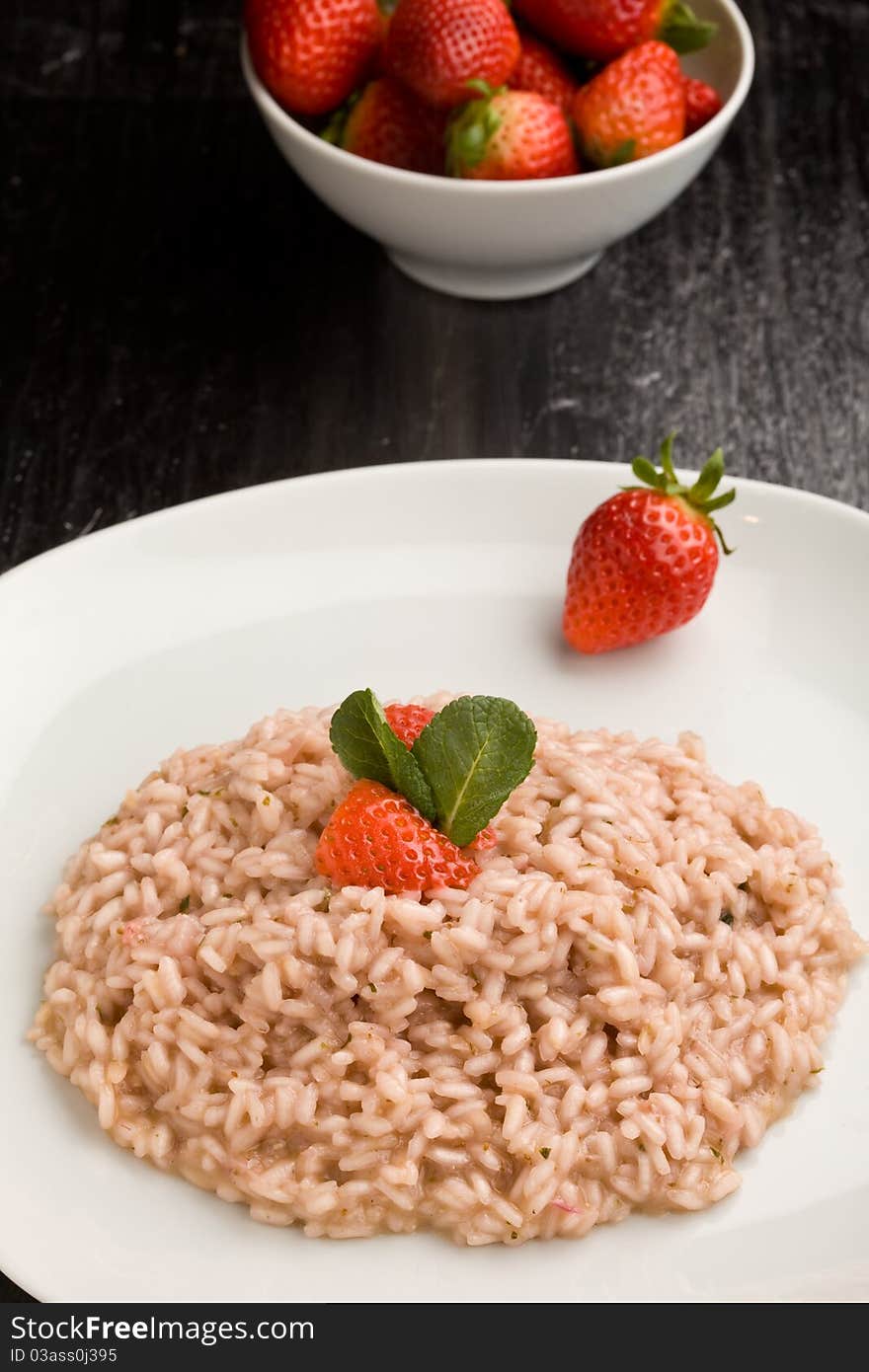 Photo of delicious risotto with strawberries and champagne on black table