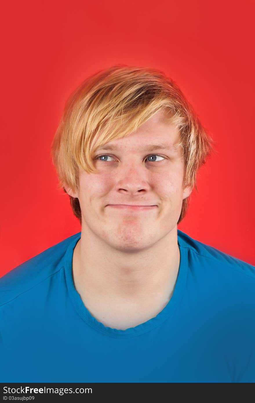 Displeased young man showing no emotions on red background