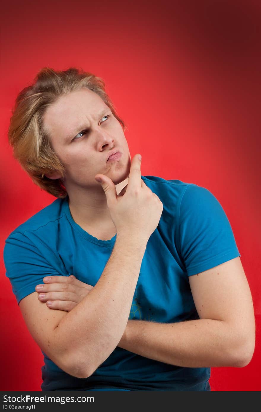 Young man with thoughtful pose on red background. Young man with thoughtful pose on red background