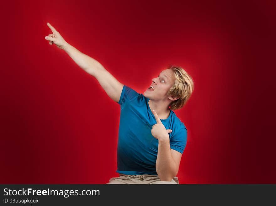 Man pointing on red copy-space with wild facial expression. Man pointing on red copy-space with wild facial expression