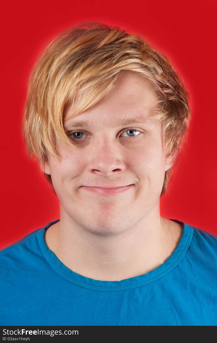 Displeased young man showing no emotions on red background. Displeased young man showing no emotions on red background