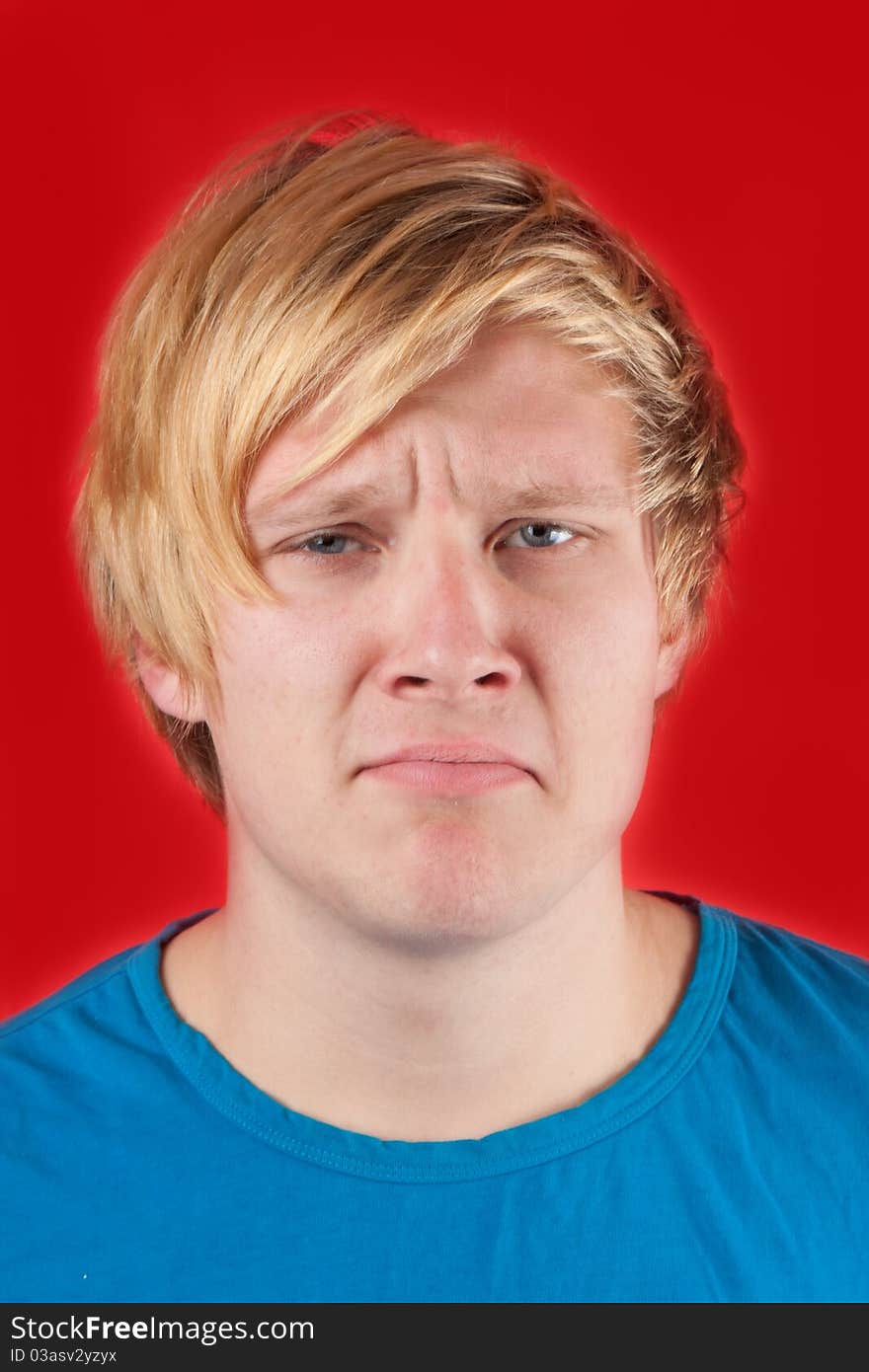 Displeased young man showing no emotions on red background. Displeased young man showing no emotions on red background