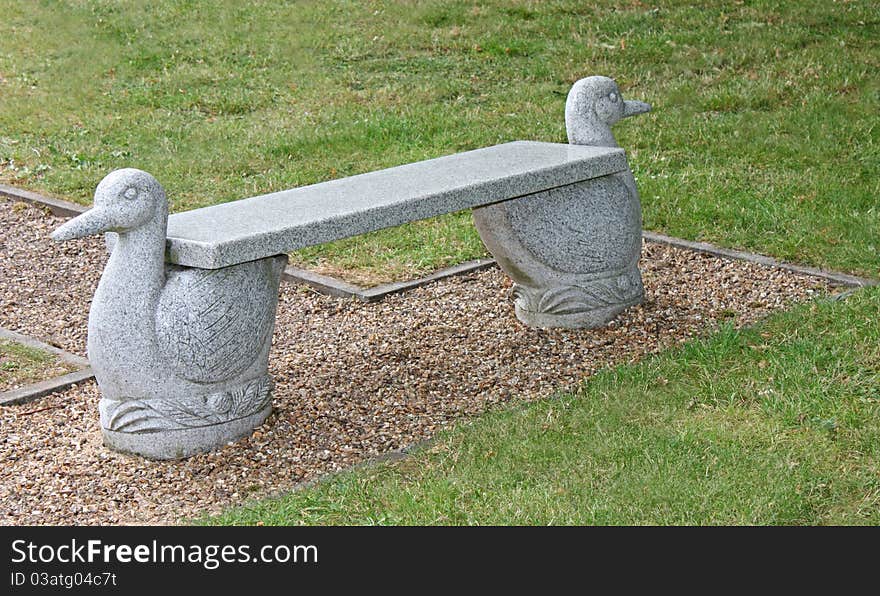 An Outdoors Stone Bench with Bird Design Supports.