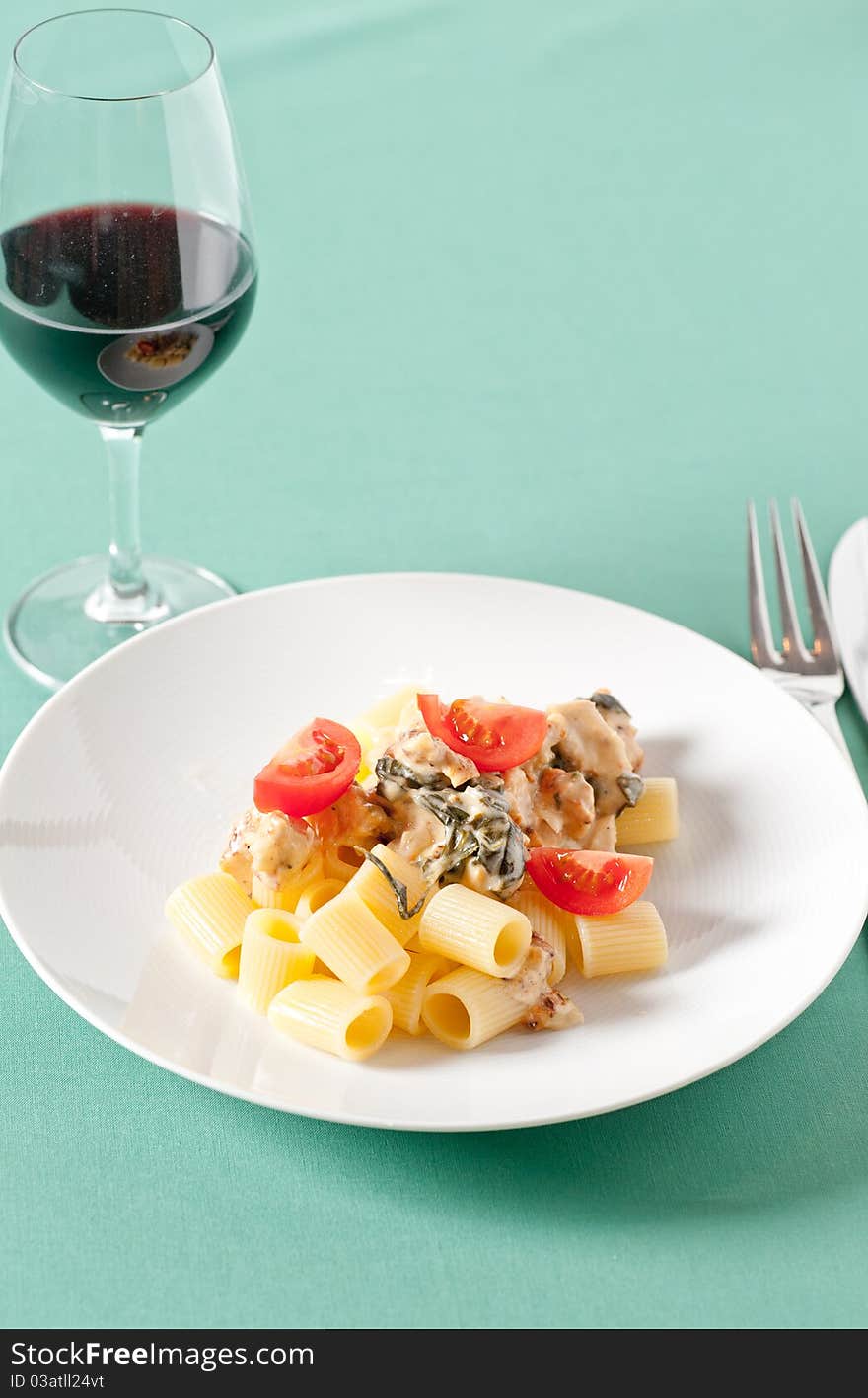 Chicken with pasta and fresh cherry tomatoes on a pastel tablecloth