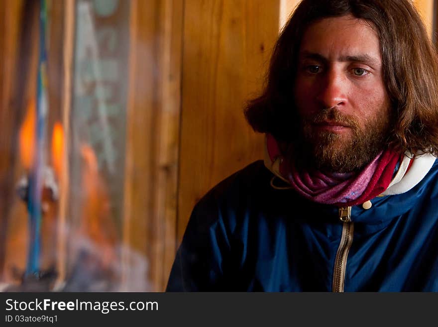 A man with long hair near a fire. A man with long hair near a fire