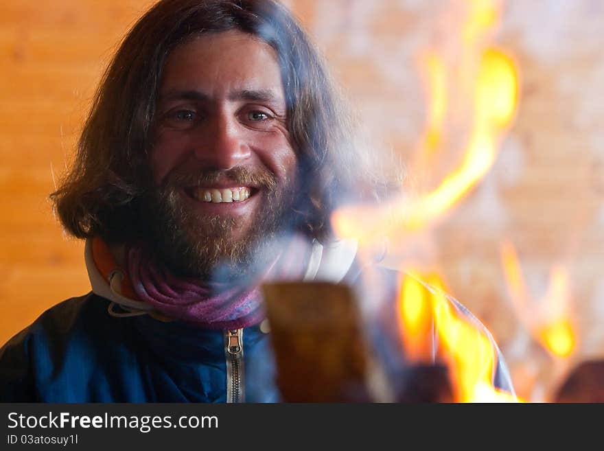 A man with long hair near a fire. A man with long hair near a fire