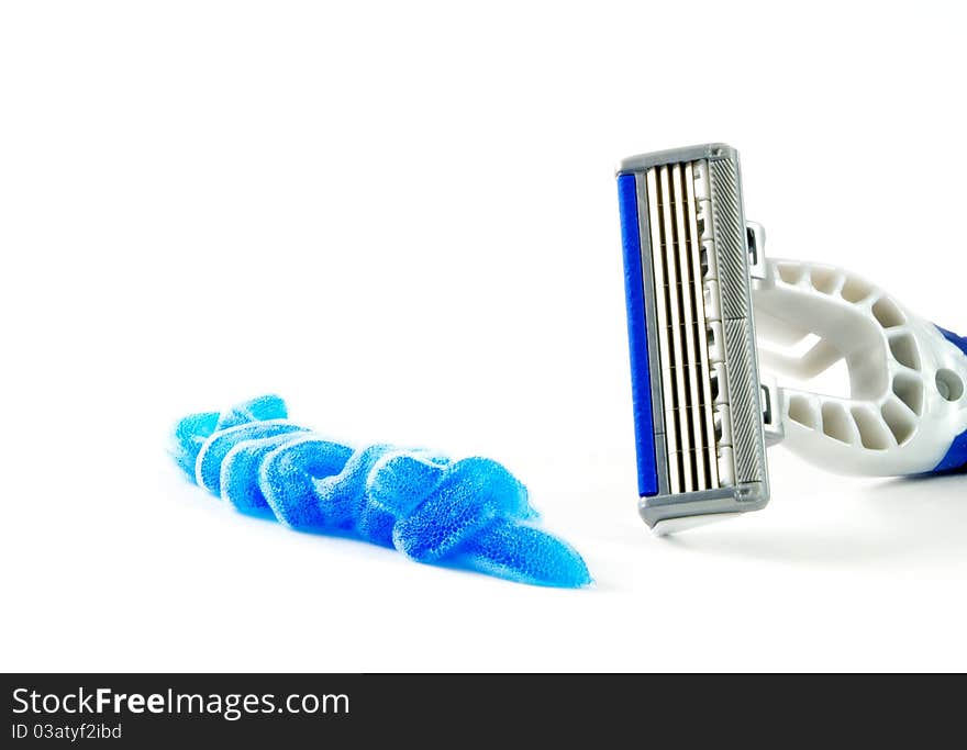 Closeup of blue shaving blade with foam on white surface