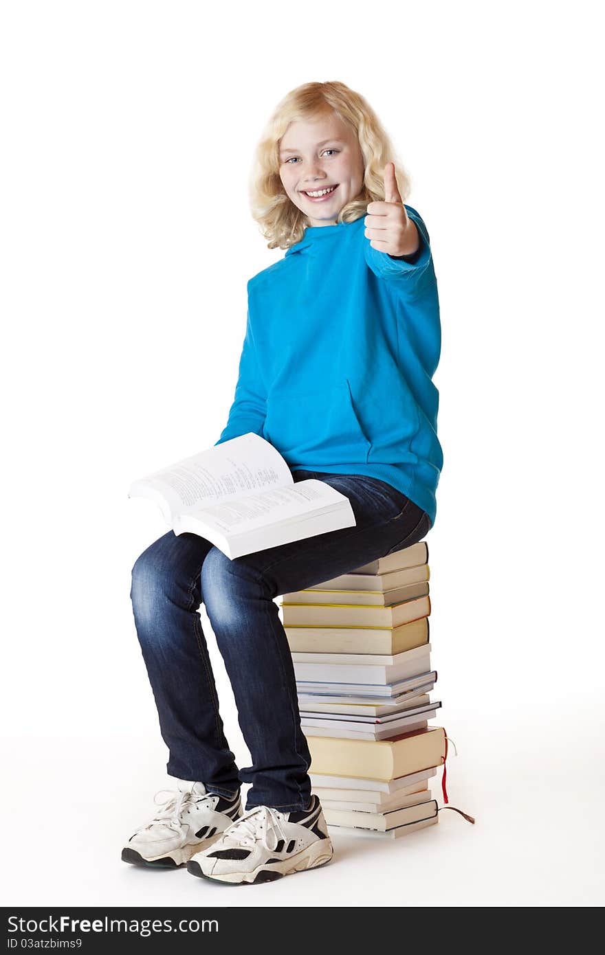 Happy schoolgirl sitting on books showing thumb