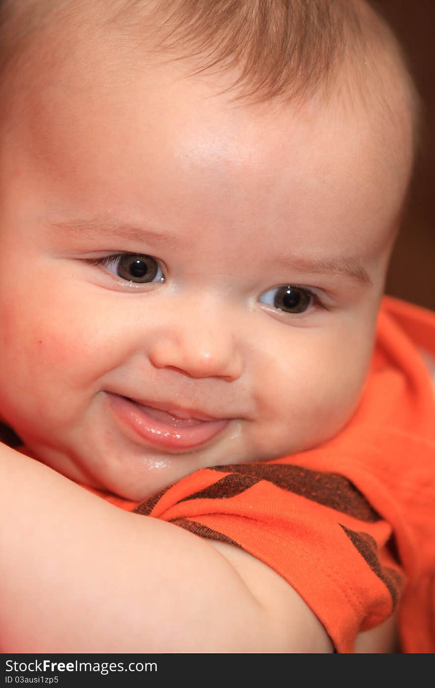 The child laughs in an orange sweater