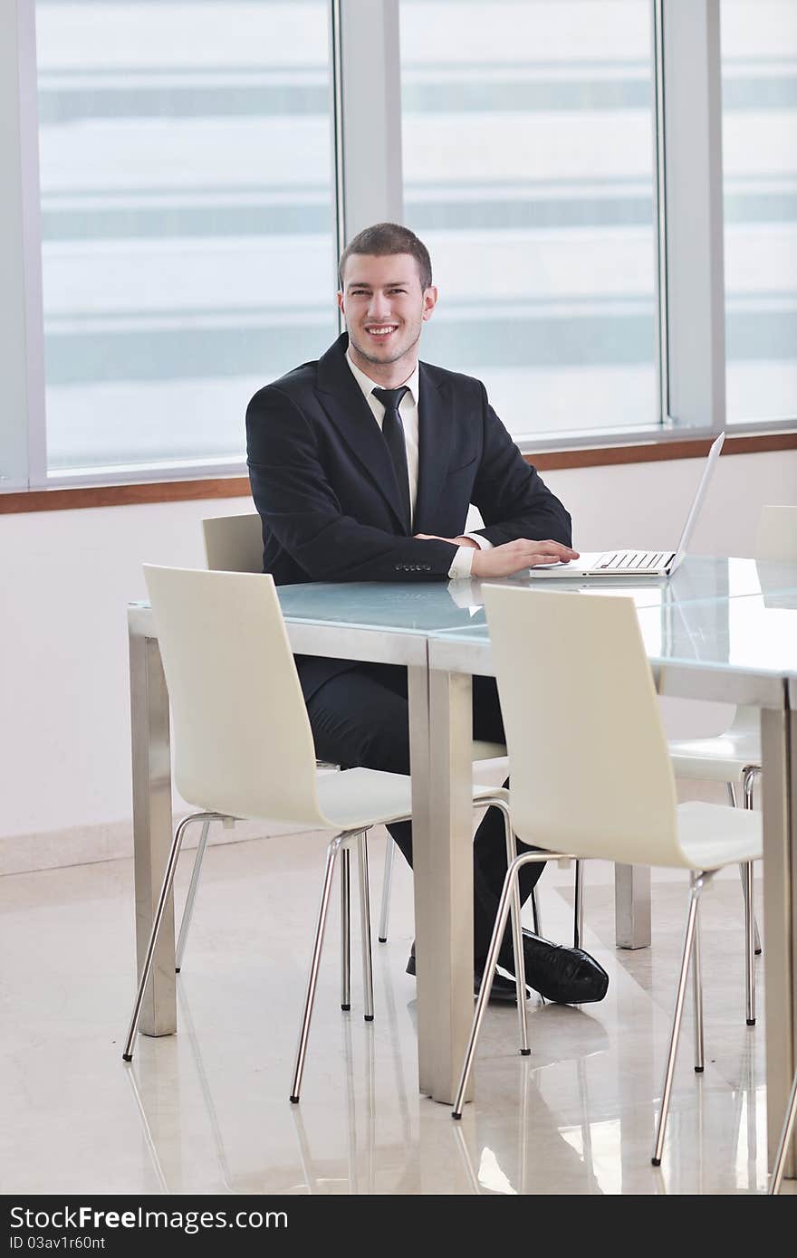 Young business man lawyer with laptop alone in big bright   conference room. Young business man lawyer with laptop alone in big bright   conference room