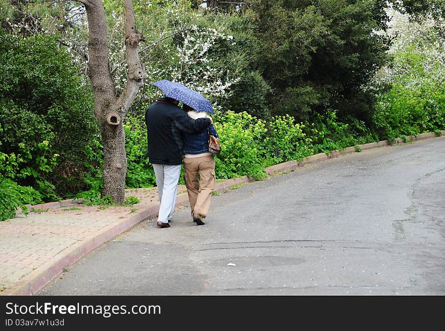 A couple walking under umbrella during rain. A couple walking under umbrella during rain