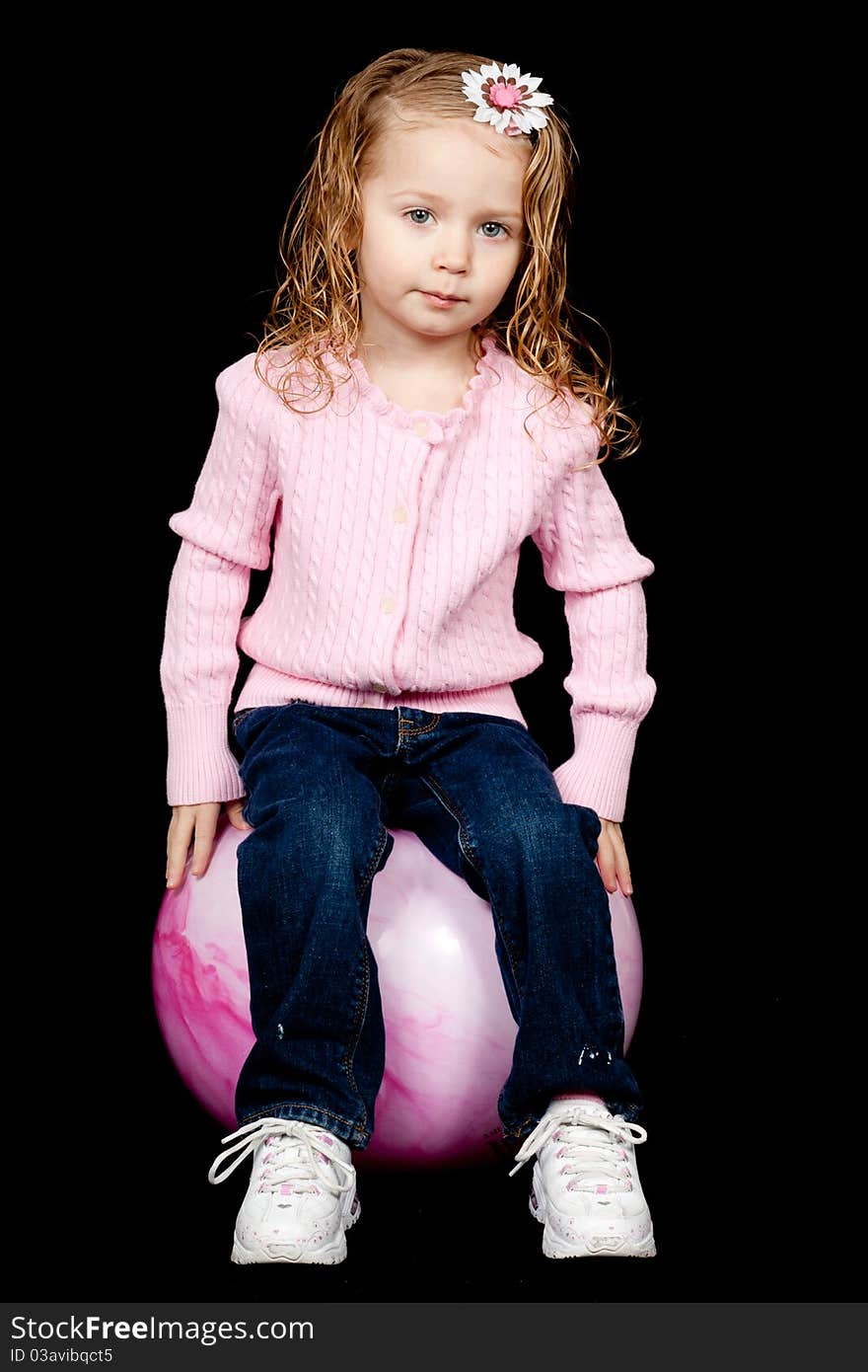 A lone content child sitting on her pink rubber ball. A lone content child sitting on her pink rubber ball.