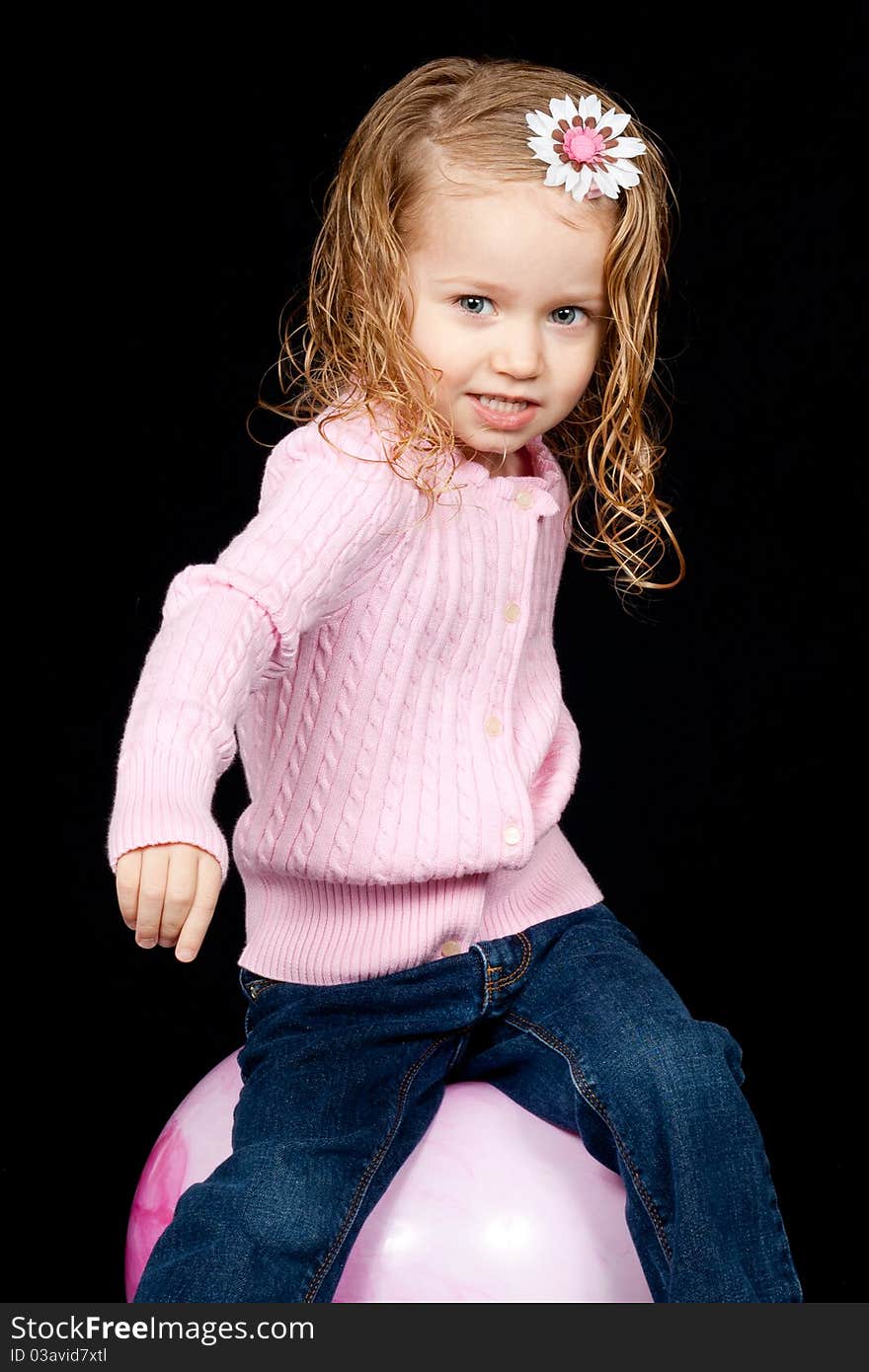 An adorable young child playing on a pink ball. An adorable young child playing on a pink ball.