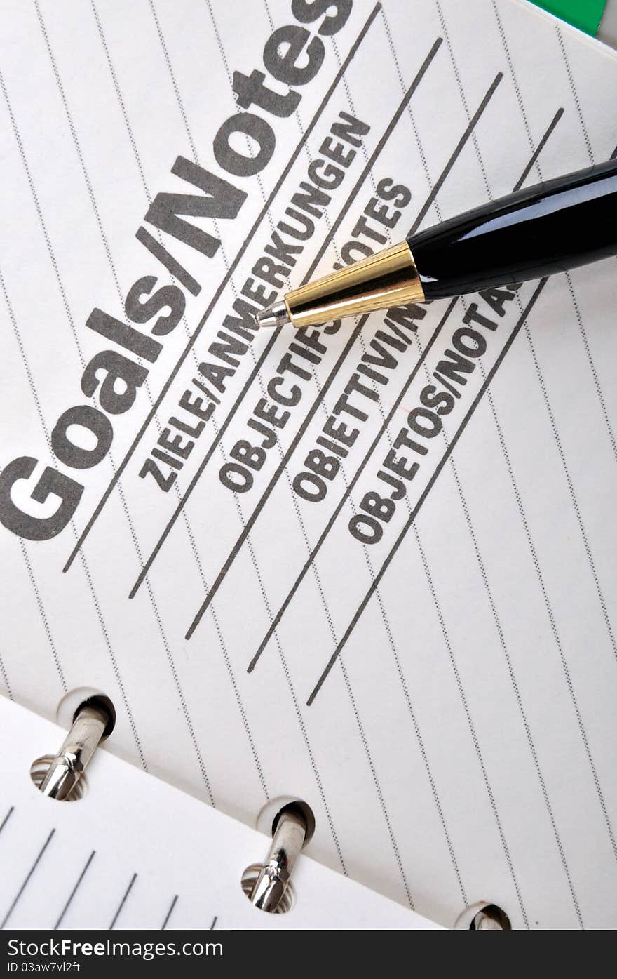 Goals plan or record in notepad and a ball pen, shown as working goals, target, focus, objective important notes and other related business concept. Goals plan or record in notepad and a ball pen, shown as working goals, target, focus, objective important notes and other related business concept.