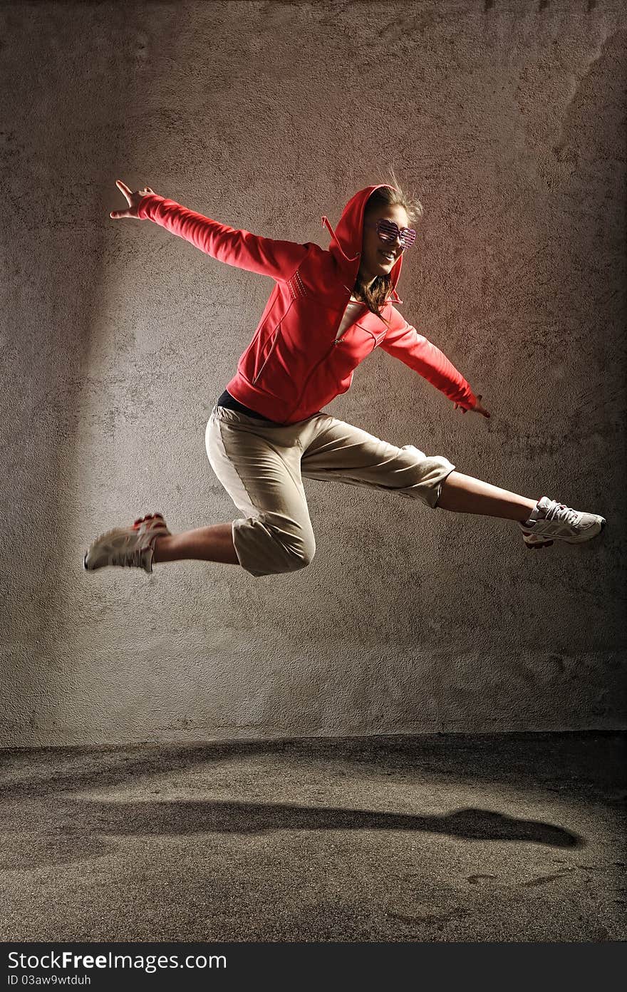 Young female dancing on the grey wall background