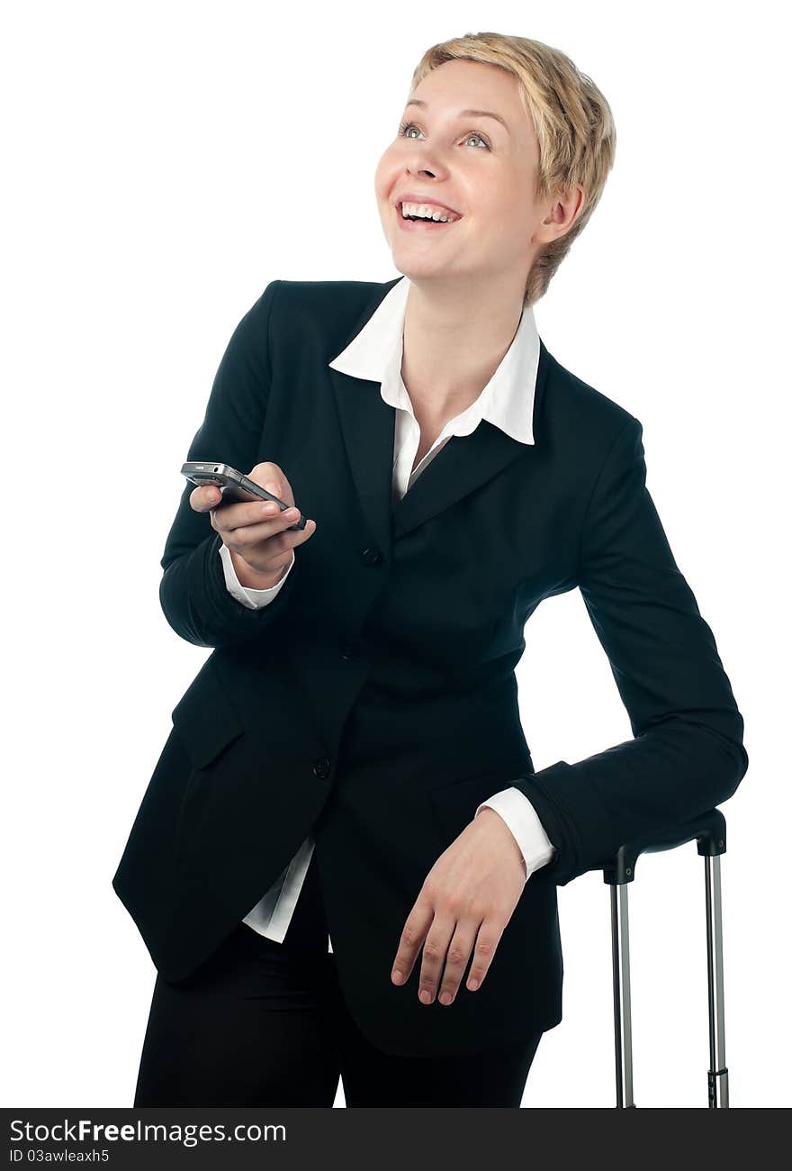 Beautiful short haired blonde business woman holding mobile phone in her hand, laughing and looking up, the other hand is on suitcase handle. Isolated on white background. Beautiful short haired blonde business woman holding mobile phone in her hand, laughing and looking up, the other hand is on suitcase handle. Isolated on white background