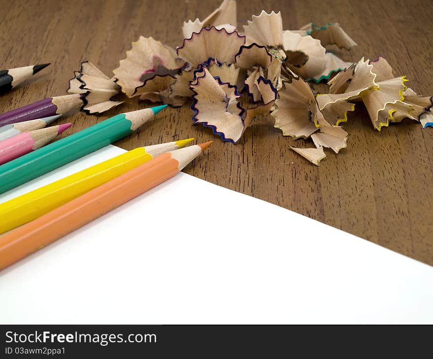 Color pencils are on a pure clean sheet near a heap of a shaving. Color pencils are on a pure clean sheet near a heap of a shaving