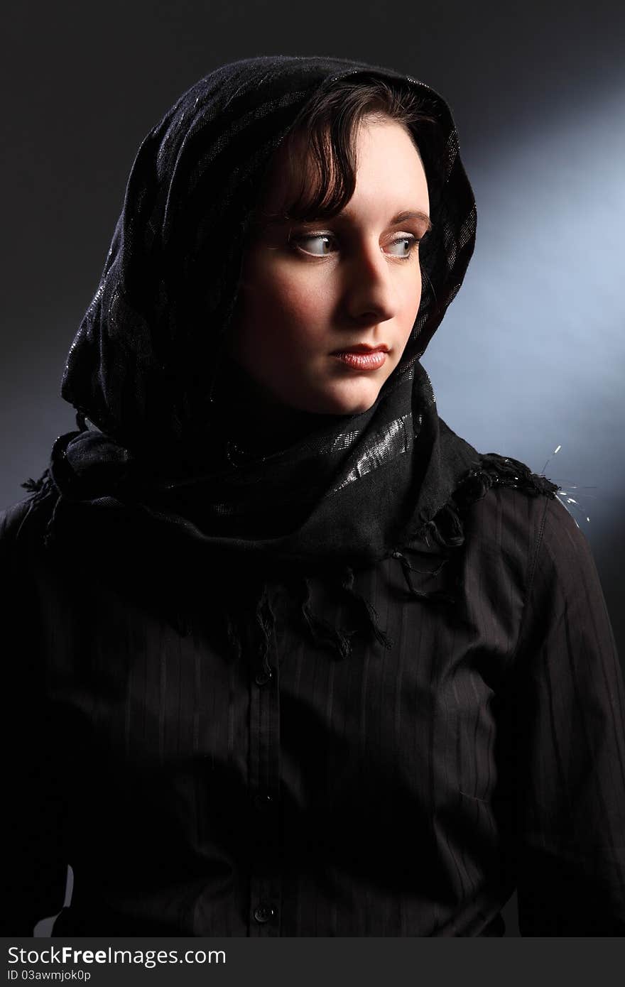 Tranquil portrait of beautiful young woman wearing black hijab, looking away over her shoulder. Tranquil portrait of beautiful young woman wearing black hijab, looking away over her shoulder.