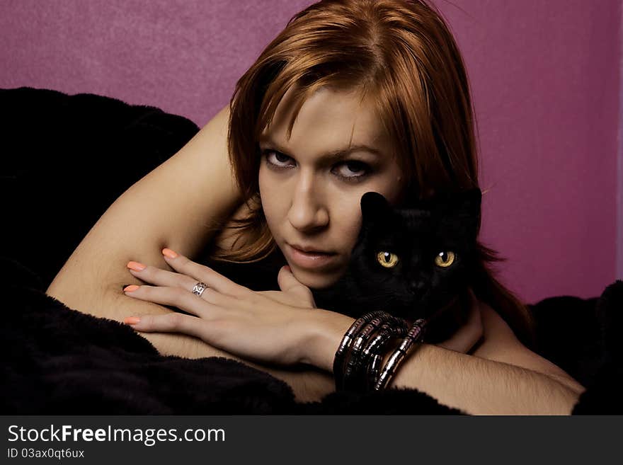 View of a beautiful woman on the bed with a black cat. View of a beautiful woman on the bed with a black cat.