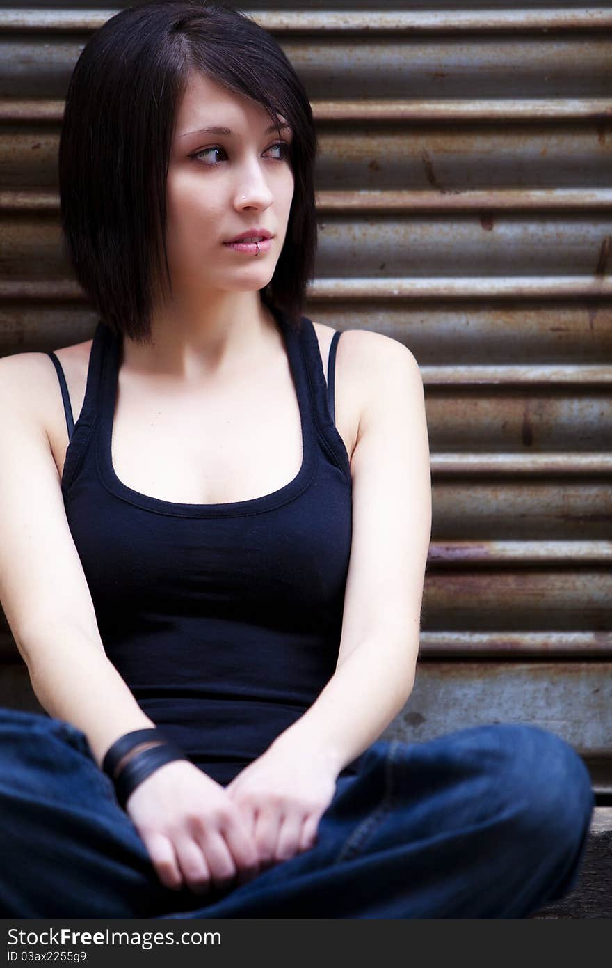 Young beautiful girl sitting on urban background. Young beautiful girl sitting on urban background