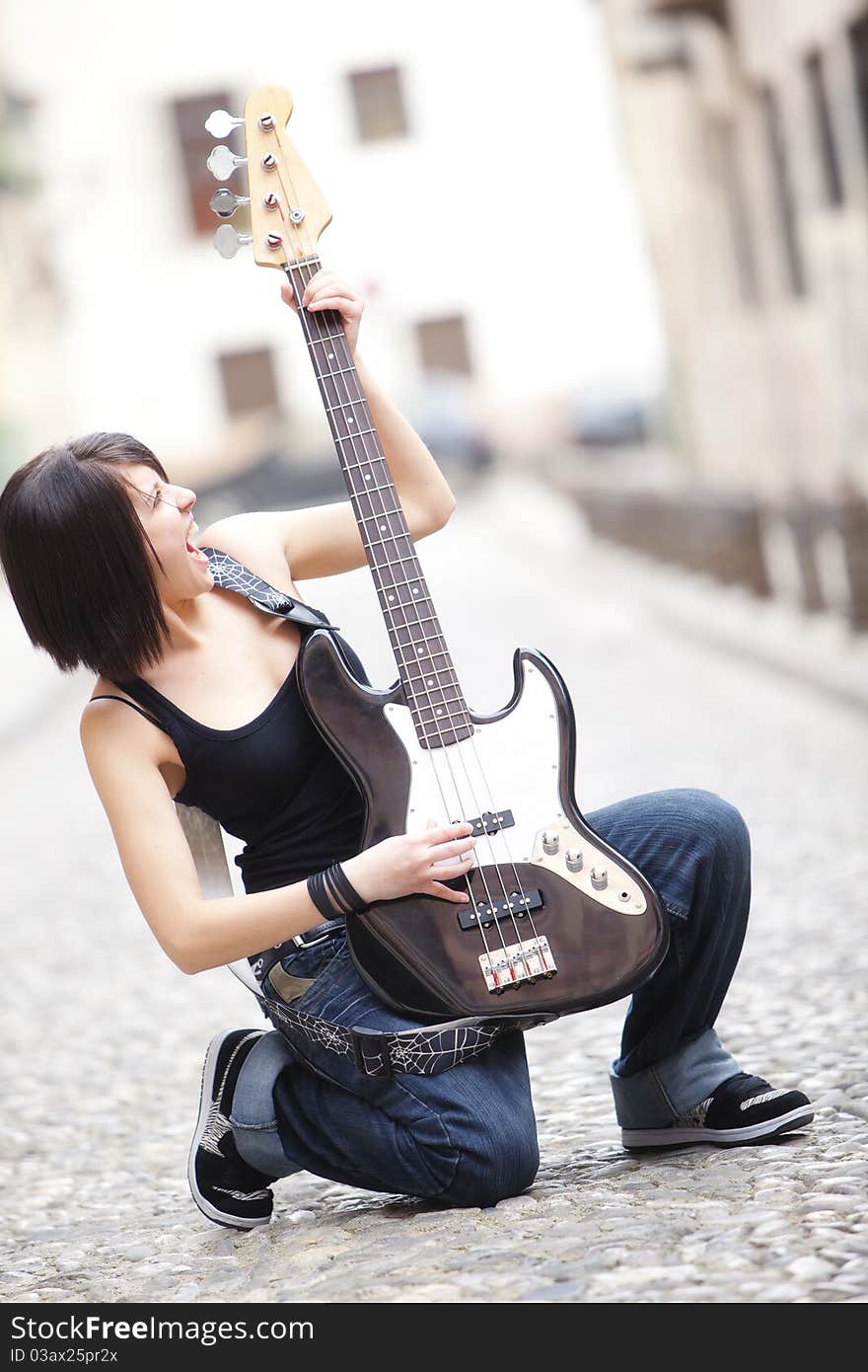 Joyful young woman playing a guitar at the street. Joyful young woman playing a guitar at the street