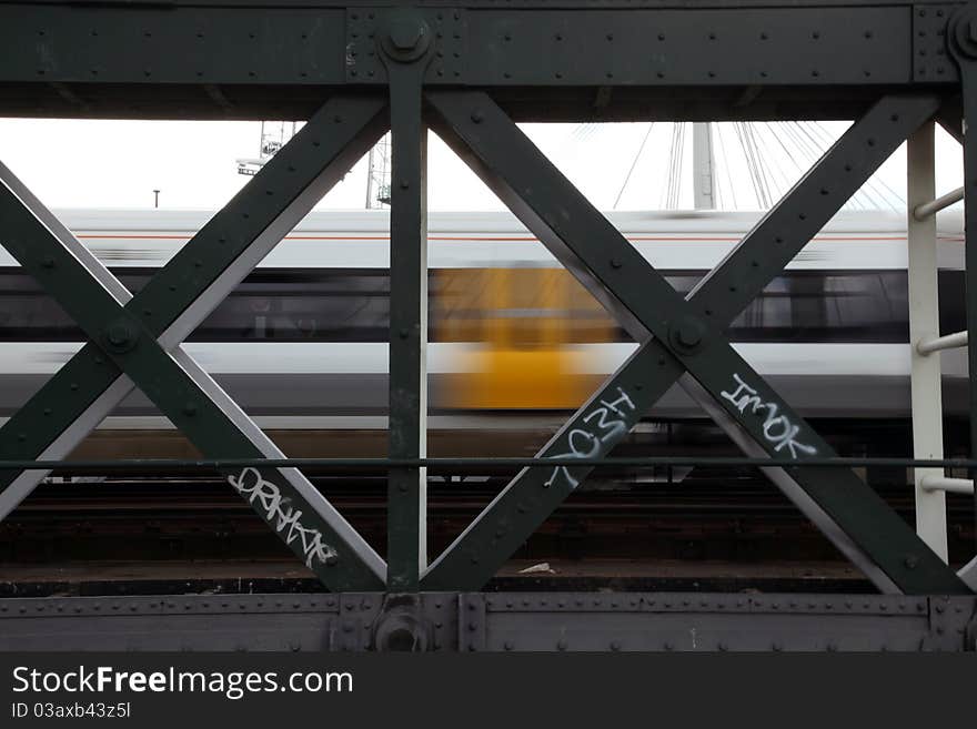 Fast train viewed trackside through steel bridge