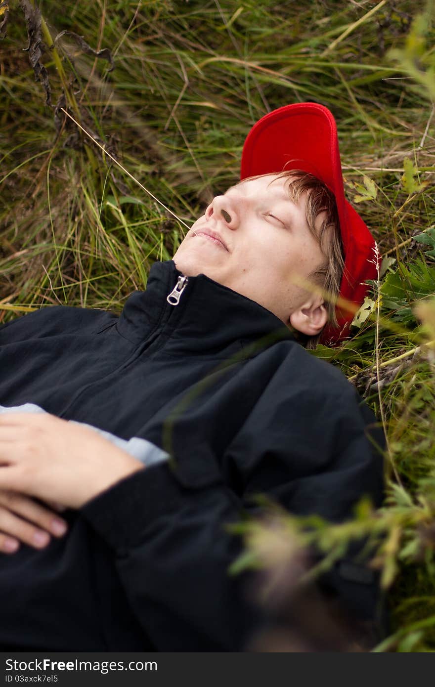 Boy in a stylish red cap resting in a field. Boy in a stylish red cap resting in a field