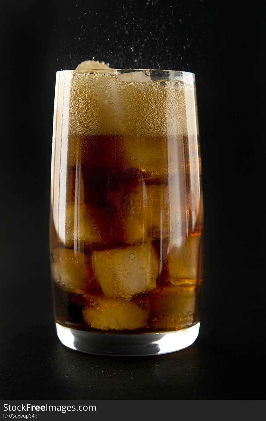 Glass with cola and ice on black background. Glass with cola and ice on black background.