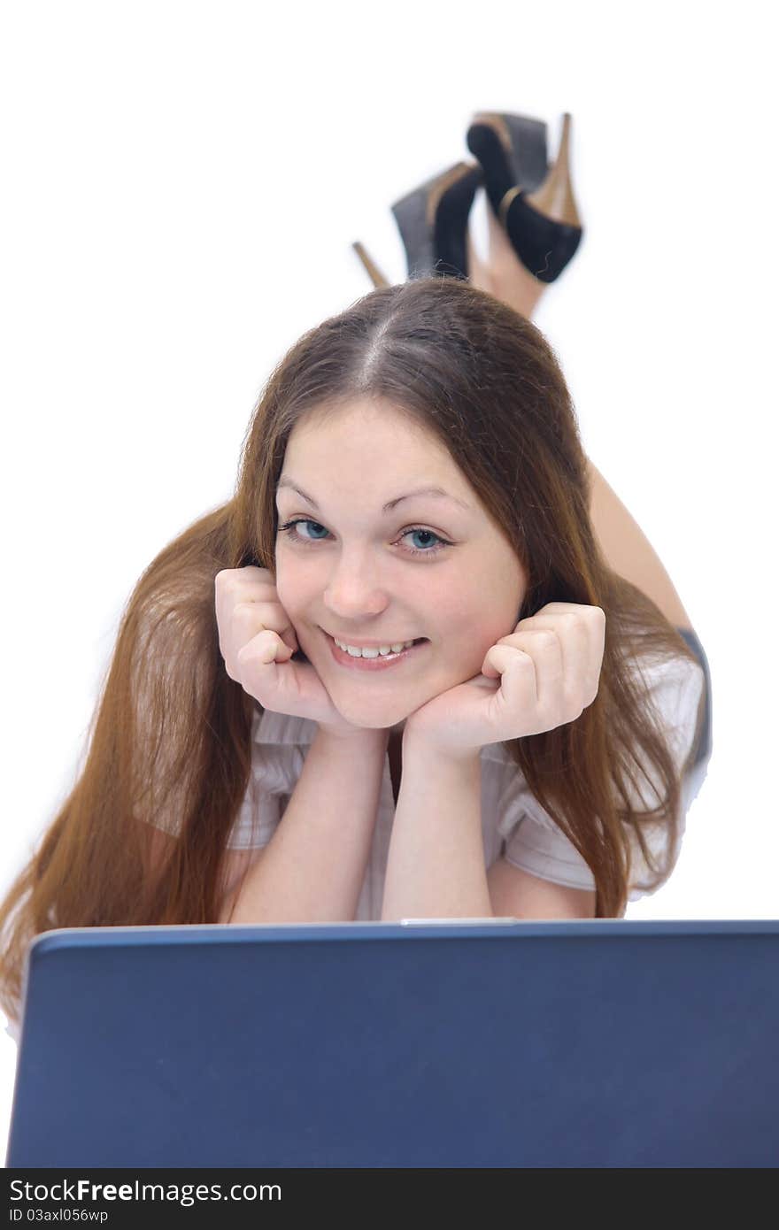 Smiling girl works with the laptop lying on the floor