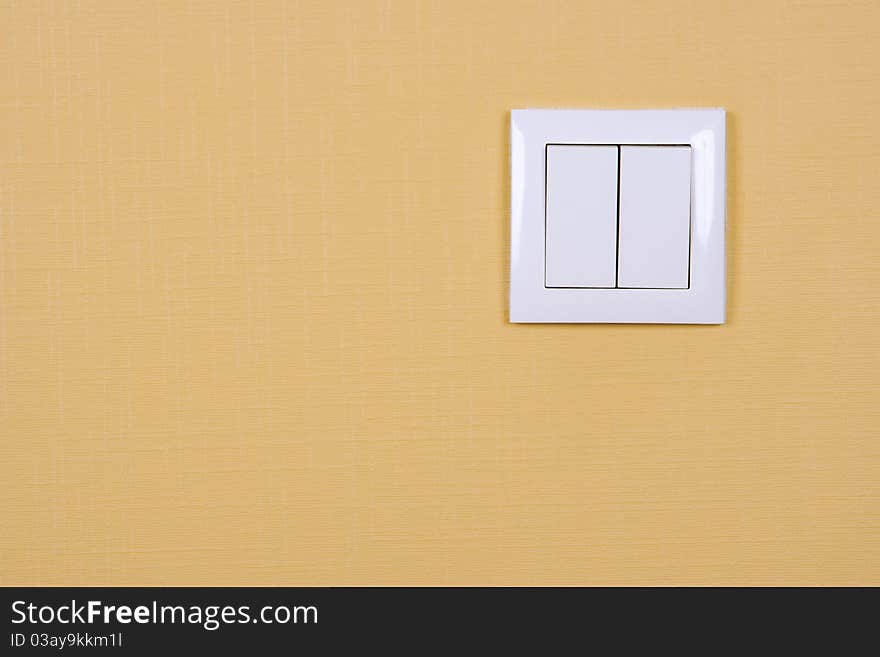 Wall-mounted electric switch in white on a yellow wall