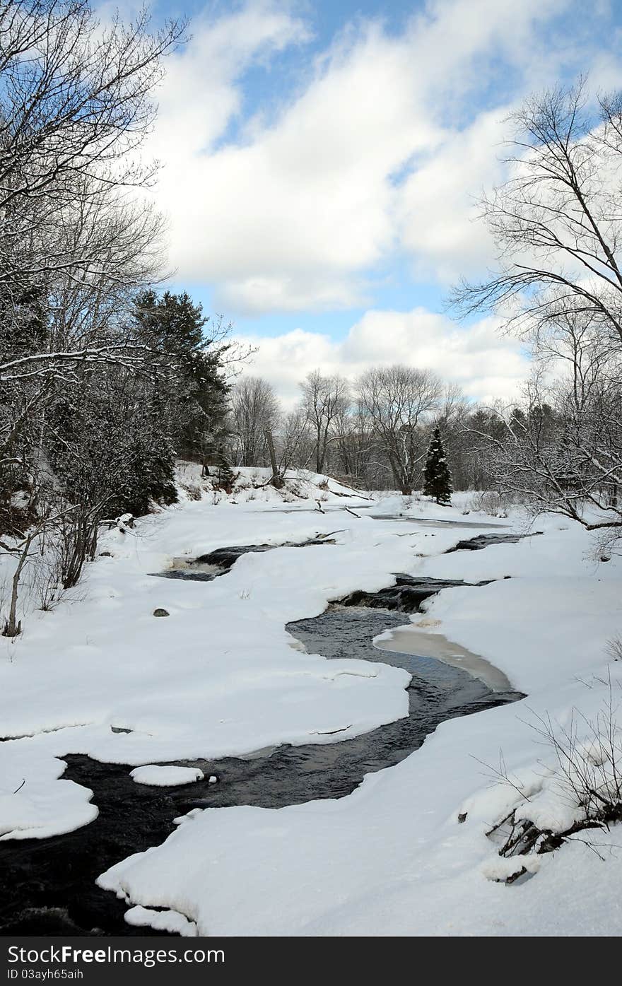 Beautiful river cascading over rocks with trees and blue sky, in winter. Beautiful river cascading over rocks with trees and blue sky, in winter