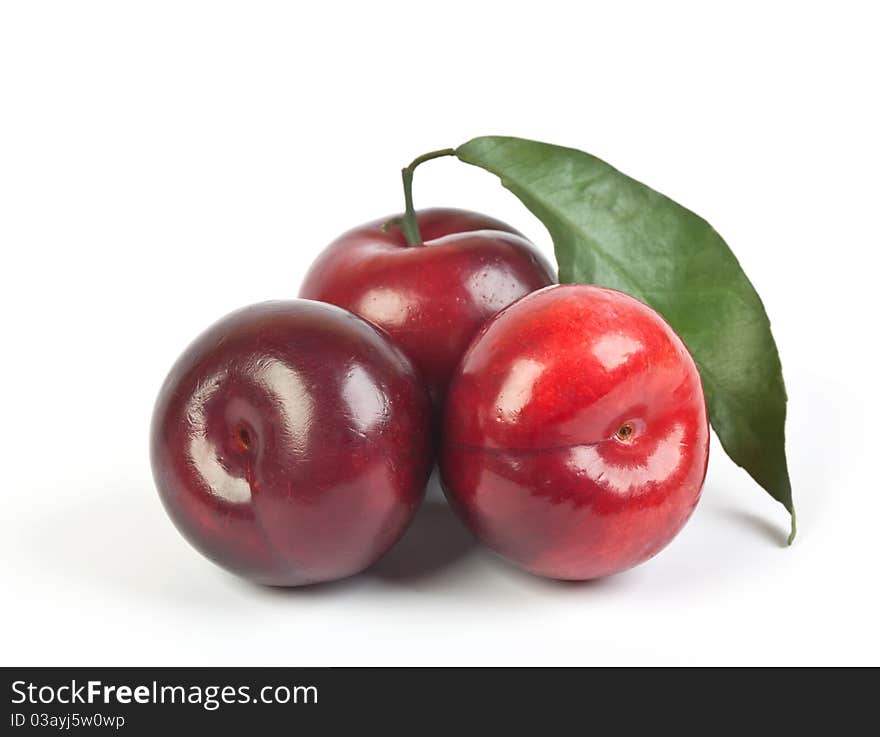 Three Ripe Plums With Green Leaf