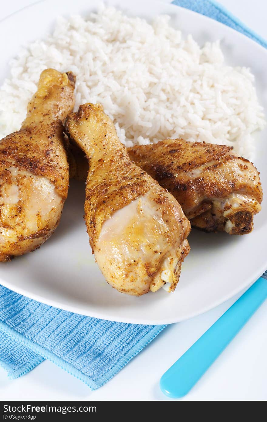 Roasted chicken legs with boiled rice on a plate