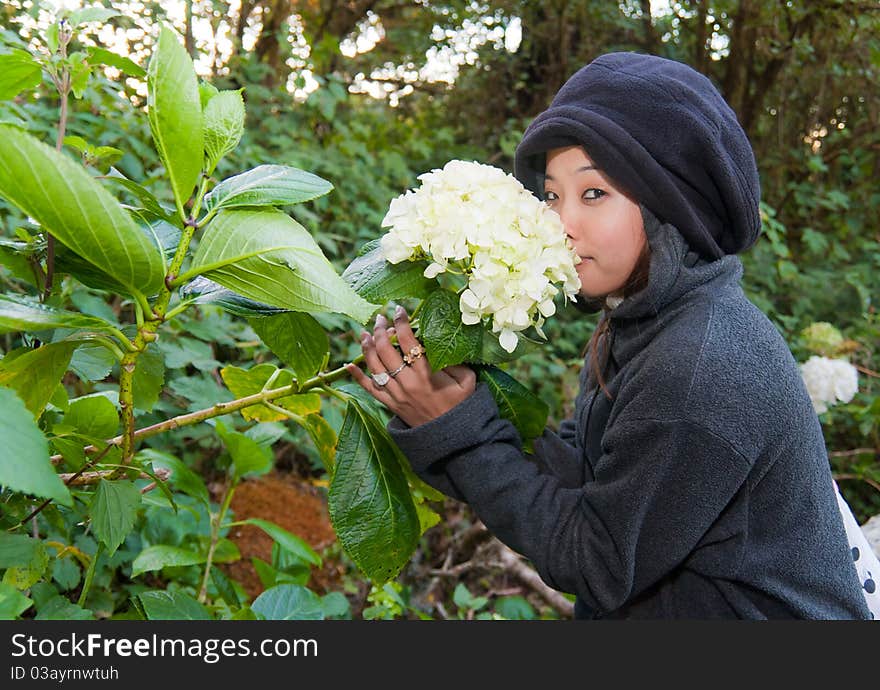 Young woman smelling flower in the forest