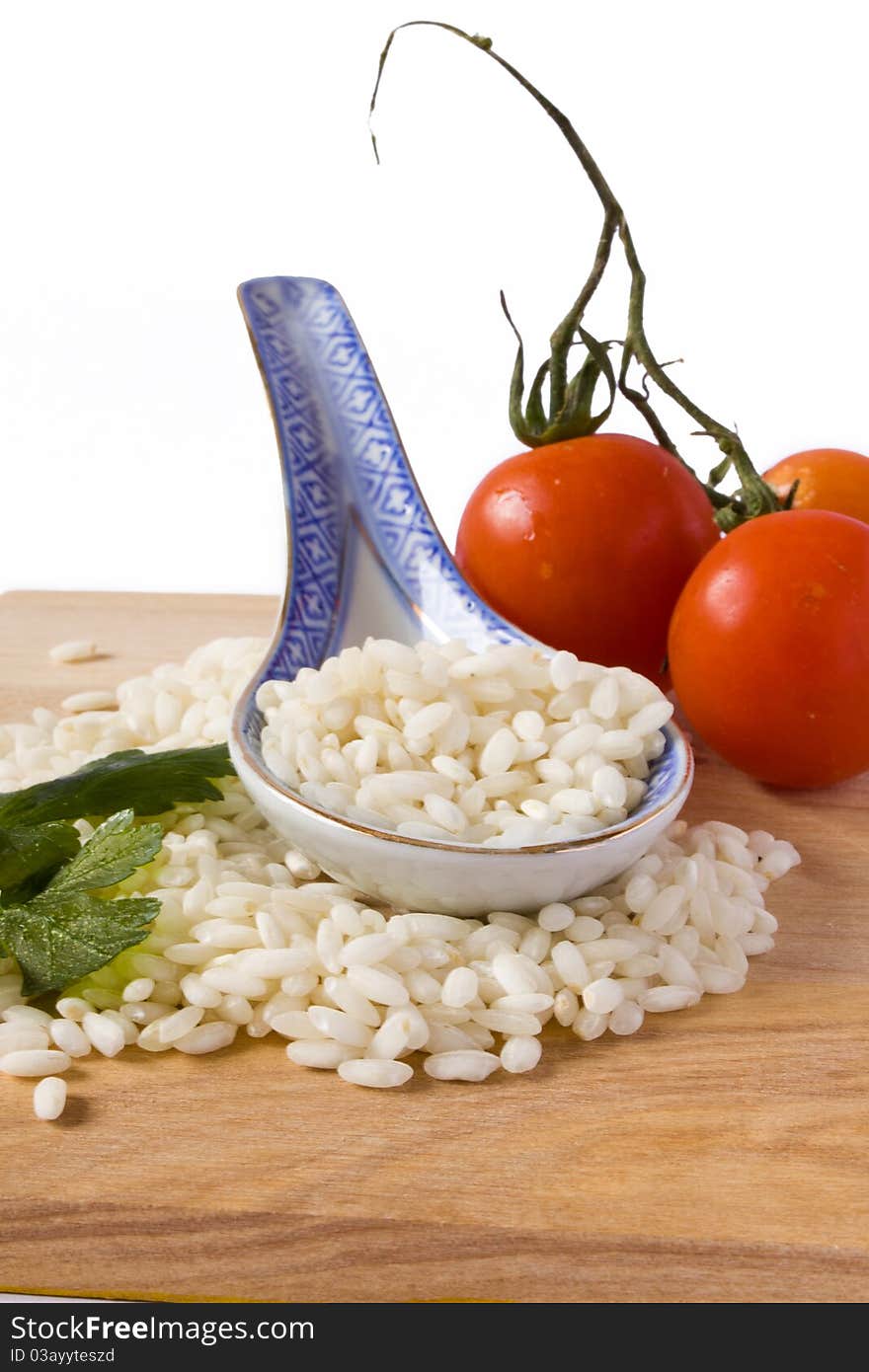 Heap of rice and porcelain spoon with tomato