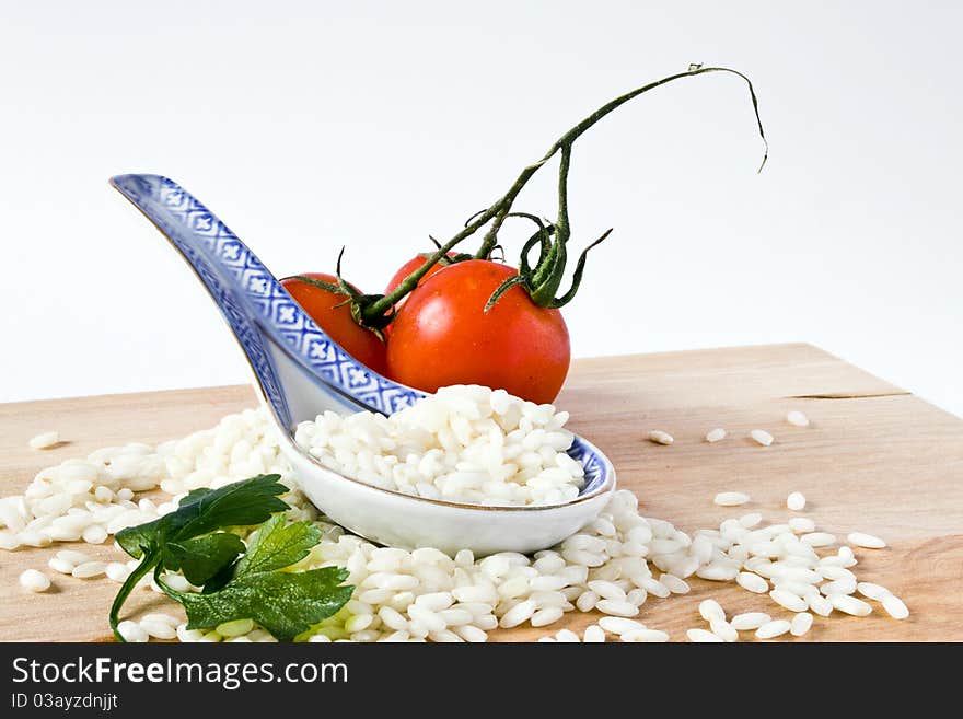 Heap of rice and porcelain spoon with tomato